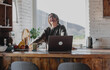 © olezzo - Happy woman in sweater laughing with laptop in rustic countryside kitchen with nature view