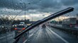 © Sharma - Rainy highway view through windshield with active wiper blades clearing water drops,cars driving under stormy clouds in evening traffic