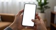 © Hypnyo - Blank smartphone screen held with both hands in a bright, cozy living room with soft daylight, ideal for UI or app mockups