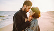 © maxbelchenko - A stylish young couple strolls together along the beach at sunset. The young woman and man enjoy the freedom of the seascape in the sun's rays. Conceptual images of love, nature, and relaxation.