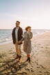 © maxbelchenko - A stylish young couple strolls together along the beach at sunset. The young woman and man enjoy the freedom of the seascape in the sun's rays. Conceptual images of love, nature, and relaxation.