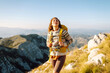 © maxbelchenko - A young woman with hiking backpack stands on mountain trail on sunny day. Female hiker with a yellow backpack enjoys mountain scenery at sunset. Concepts of adventure, freedom. Active lifestyle.