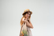 © Volodymyr_sh - Smiling young woman in straw hat and summer dress holding reusable mesh bag with vegetables, eco shopping lifestyle concept