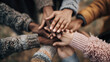 © NawManusia - Diverse group of people showing unity and teamwork by stacking their hands together in a powerful gesture of support and collaboration.