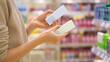 © Pavel - Customer Reading the Ingredient Labels Compares Two Skincare Products in Beauty Store. Close-up of a Female Hands, Woman Choosing Cosmetic Product. Makeup Selection. Conscious Choice. Mindful Shopping