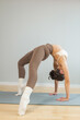 © руслан малыш - Young woman practicing advanced yoga backbend indoors. Wheel pose with strong arch, flexibility and strength training on yoga mat, minimal studio interior, wellness and mindfulness concept.