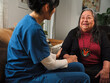 © Blue Cross MN - Native American nurse holds elder woman's hand while providing in-home care