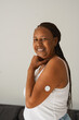 © Sabrina - Happy senior african woman posing in front of camera with diabetes patch on her arm - Healthcare, medicine and people disease concept - Vertical phonto