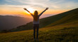 © PYo - Young woman standing with open arms on mountain meadow at sunset feeling free and happy