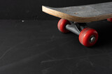 Rear view of a skateboard deck with red wheels fading into dark space. Clean composition ideal for urban sports themes and text placement.