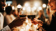 © Bonsales - People clinking red wine glasses, celebrating a special occasion with a toast at an upscale evening event