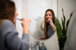 © Zoran Jesic - Woman brushing teeth in bathroom mirror reflection