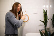 © Zoran Jesic - Woman brushing long hair in bathroom mirror reflection