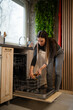 © Zoran Jesic - Woman loading dishwasher with cutlery in modern kitchen