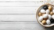 © lililia - Bowl holds fresh eggs of various colors on a white wooden surface with room for text or design elements