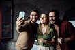 © Novak - Happy startup team taking a group selfie with a smartphone in a modern office.