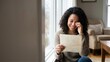 © dreamdes - African American woman crying happy tears while reading a heartfelt letter near a window. Emotional moment of joy and love for Valentines Day