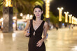 © JackF - Stylish young lady enjoying evening stroll near the waterfront surrounded by city lights in Barcelona