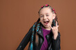 © New Africa - Cute girl with stylish braids showing rock gesture on brown background