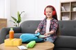 © New Africa - Girl with headphones packing her backpack for school on sofa at home. Space for text