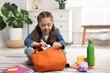 © New Africa - Girl packing her backpack for school at home. Space for text