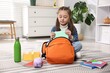 © New Africa - Girl packing her backpack for school at home. Space for text