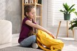 © New Africa - Girl packing her backpack for school at home. Space for text