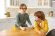 © New Africa - Cute brothers with orange juice at wooden table in kitchen