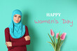 © New Africa - Happy Women's day celebration. Muslim woman in hijab and bouquet of tulips on turquoise background