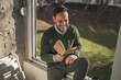 © Miljan Živković - Smiling man reading book by window enjoying quiet moment