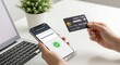 © QuiinL - Hands holding a smartphone displaying a successful payment confirmation and a credit card, with a laptop and plant in the background.