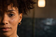 © Wavebreak Media - African American woman gazing at camera in warm room wearing gold hoop earring, copy space