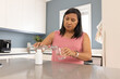 © Wavebreak Media - Mature woman pouring water from swing-top glass bottle into small drinking glass at kitchen island