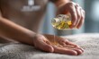 © VictoriaEmerson - Therapist pouring golden aromatherapy oil from a glass bottle into a hand, preparing for a relaxing spa massage treatment