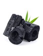 © Meiga - Black, charred wood pieces arranged with vibrant green grass blades. The charcoal segments vary in size and texture. They rest on a pure white backdrop