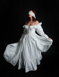© faestock - full length portrait beautiful female model wearing antique white historical ghost bride wedding dress gown, veiled mask blindfold covering face. isolated walking figure on dark studio background.