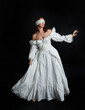 © faestock - full length portrait beautiful female model wearing antique white historical ghost bride wedding dress gown, veiled mask blindfold covering face. isolated walking figure on dark studio background.