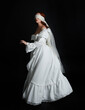 © faestock - full length portrait beautiful female model wearing antique white historical ghost bride wedding dress gown, veiled mask blindfold covering face. isolated walking figure on dark studio background.