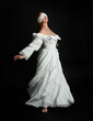 © faestock - full length portrait beautiful female model wearing antique white historical ghost bride wedding dress gown, veiled mask blindfold covering face. isolated walking figure on dark studio background.