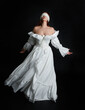 © faestock - full length portrait beautiful female model wearing antique white historical ghost bride wedding dress gown, veiled mask blindfold covering face. isolated walking figure on dark studio background.