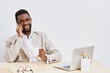 © SHOTPRIME STUDIO - Smiling man talking on mobile phone while holding coffee mug sitting at a desk with laptop and glasses on a plain white background. Business lifestyle concept