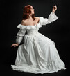 © faestock - Full length portrait beautiful female model wearing antique white historical ghost bride wedding dress gown. classical elegant sitting pose, Isolated figure on dark studio background