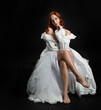 © faestock - Full length portrait beautiful female model with red hair wearing a antique white historical ghost bride wedding dress gown. classical elegant sitting pose, Isolated figure on dark studio background