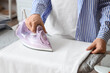 © Pixel-Shot - Woman ironing bed sheet on ironing board at home, closeup