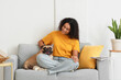 © Pixel-Shot - Beautiful young African-American woman with cute French bulldog sitting on sofa at home