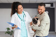 © Pixel-Shot - Female African-American veterinarian with owner and pug dog in hall of clinic