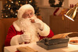 © Pixel-Shot - Santa Claus with typewriter and cookies drinking milk while writing Christmas story at night