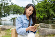 © leungchopan - Woman using cellphone sitting at park