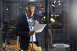 © BuyoutReese06/peopleimages.com - Dark, documents and thinking with business man in glass office for decision, ideas or planning. Night, paperwork and reading with mature person in financial workplace for agenda, report or review