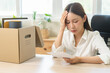© KMPZZZ - Unemployment, quitting job, desperate asian young business woman holding a resignation letter, resigning from company packing belongings, stuff in box, layoff or leaving, changing work employment.